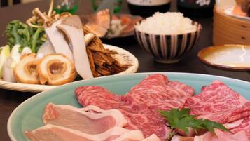 A table with various food items including meat, vegetables, and a bottle of drink.