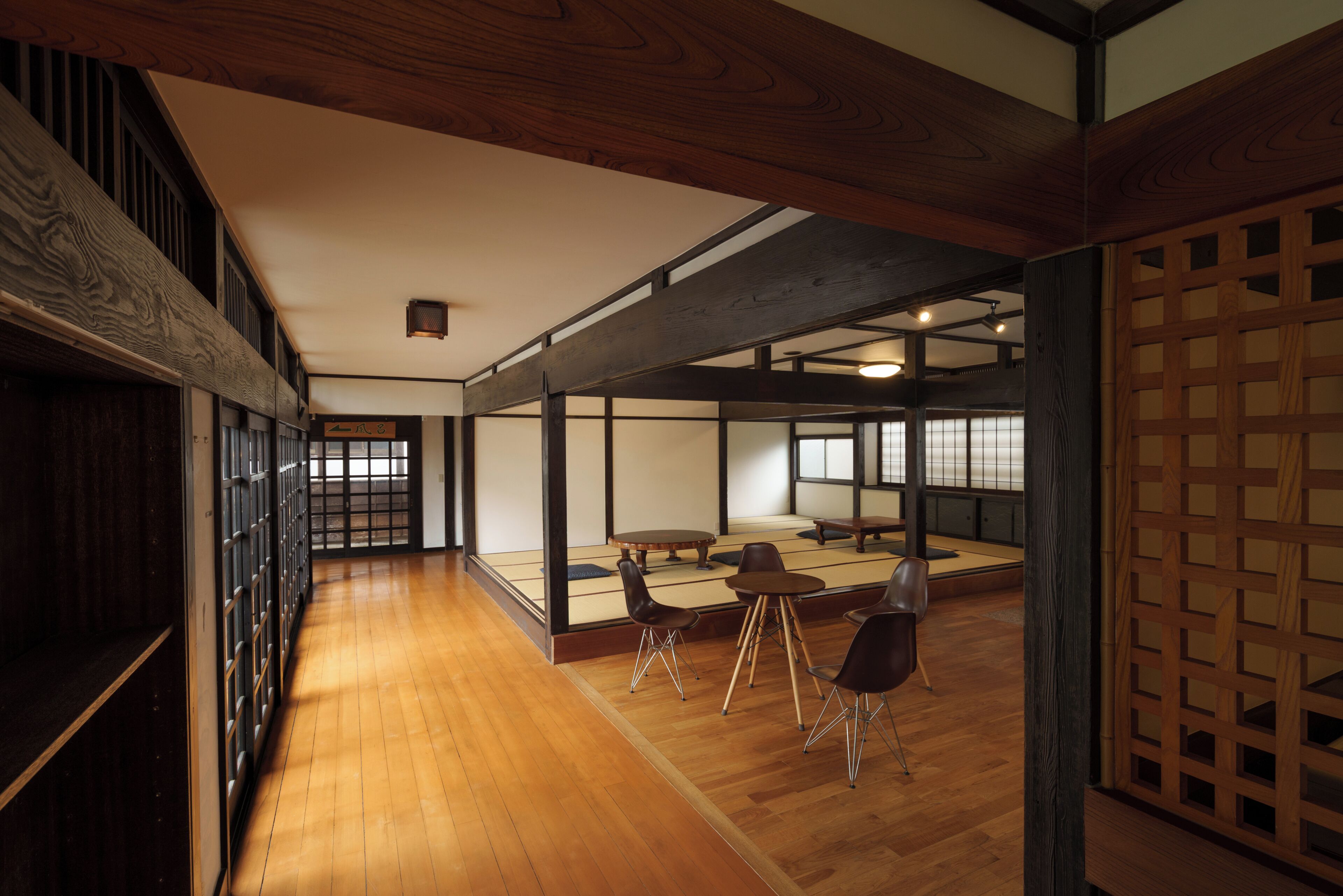 A traditional Japanese room with tatami flooring, low wooden tables, and sliding doors.