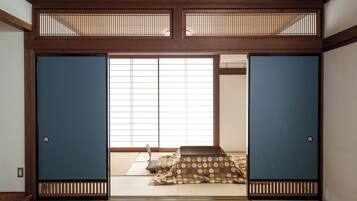 A traditional Japanese room with tatami flooring, shoji screens, and a low table with cushions.