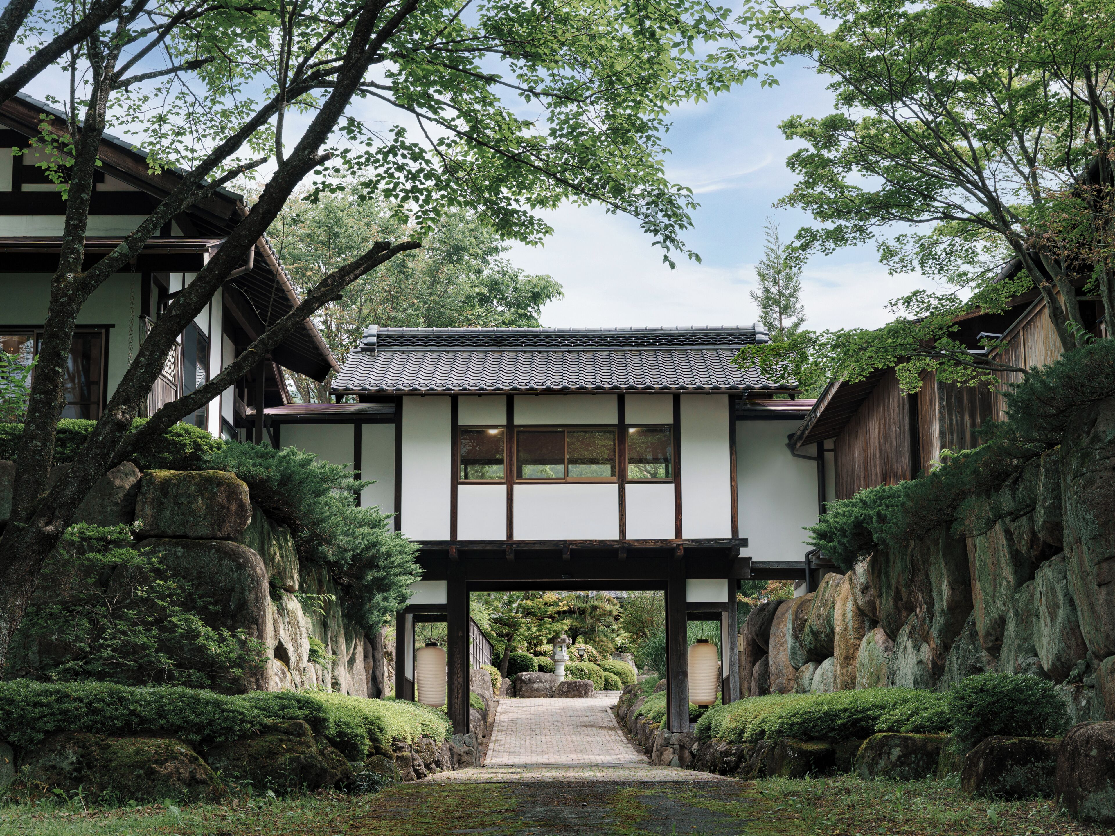 A traditional Japanese building with a tiled roof, wooden beams, and a stone pathway leading to it.
