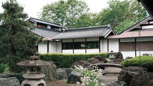 A traditional Japanese building with a tiled roof, surrounded by a rock garden and a small pagoda.