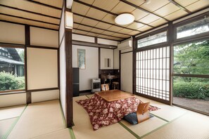 Una habitación japonesa tradicional con suelo de tatami, una mesa baja y vistas a zonas verdes.