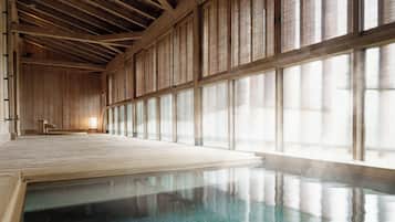 Un onsen japonais traditionnel, avec des poutres en bois, un sol recouvert de tatamis et de grandes portes coulissantes.