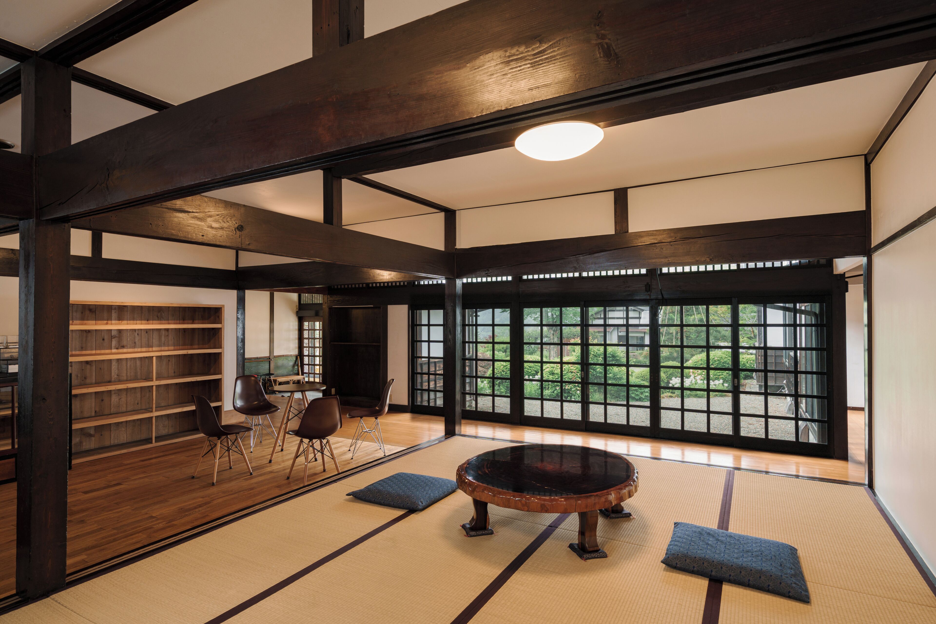 A tatami mat room with a tatami mat table, chairs, and a bookshelf.