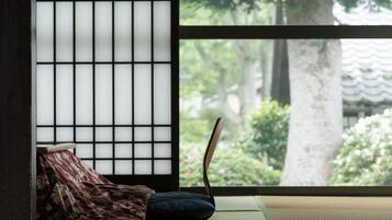 A traditional Japanese room with tatami flooring, a shoji screen, and a view of a garden.