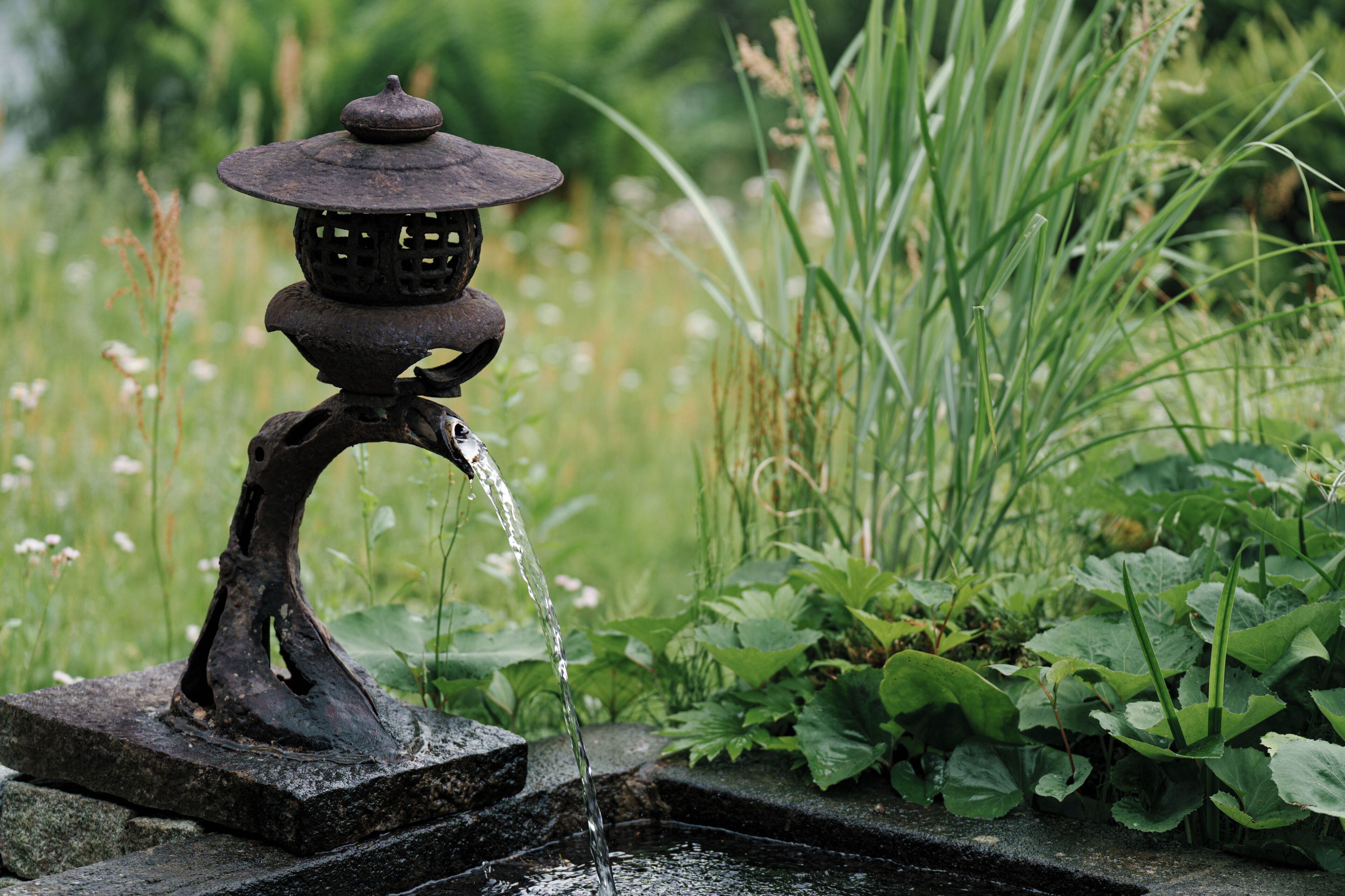 Una fuente de agua con una estructura de farol tradicional y agua que fluye de ella.