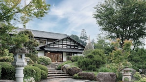 A traditional Japanese house with a tiled roof, wooden beams, and a stone lantern.
