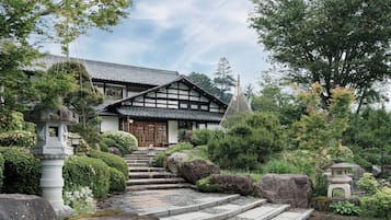Une maison traditionnelle japonaise, avec un toit recouvert de tuiles, des poutres en bois et une lanterne en pierre.