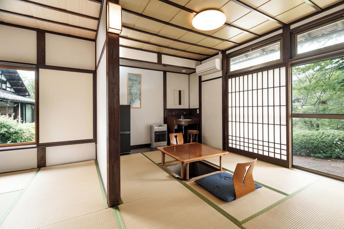 Ein traditioneller japanischer Raum mit Tatami-Bodenbelag, einem niedrigen Holztisch und Schiebetüren.