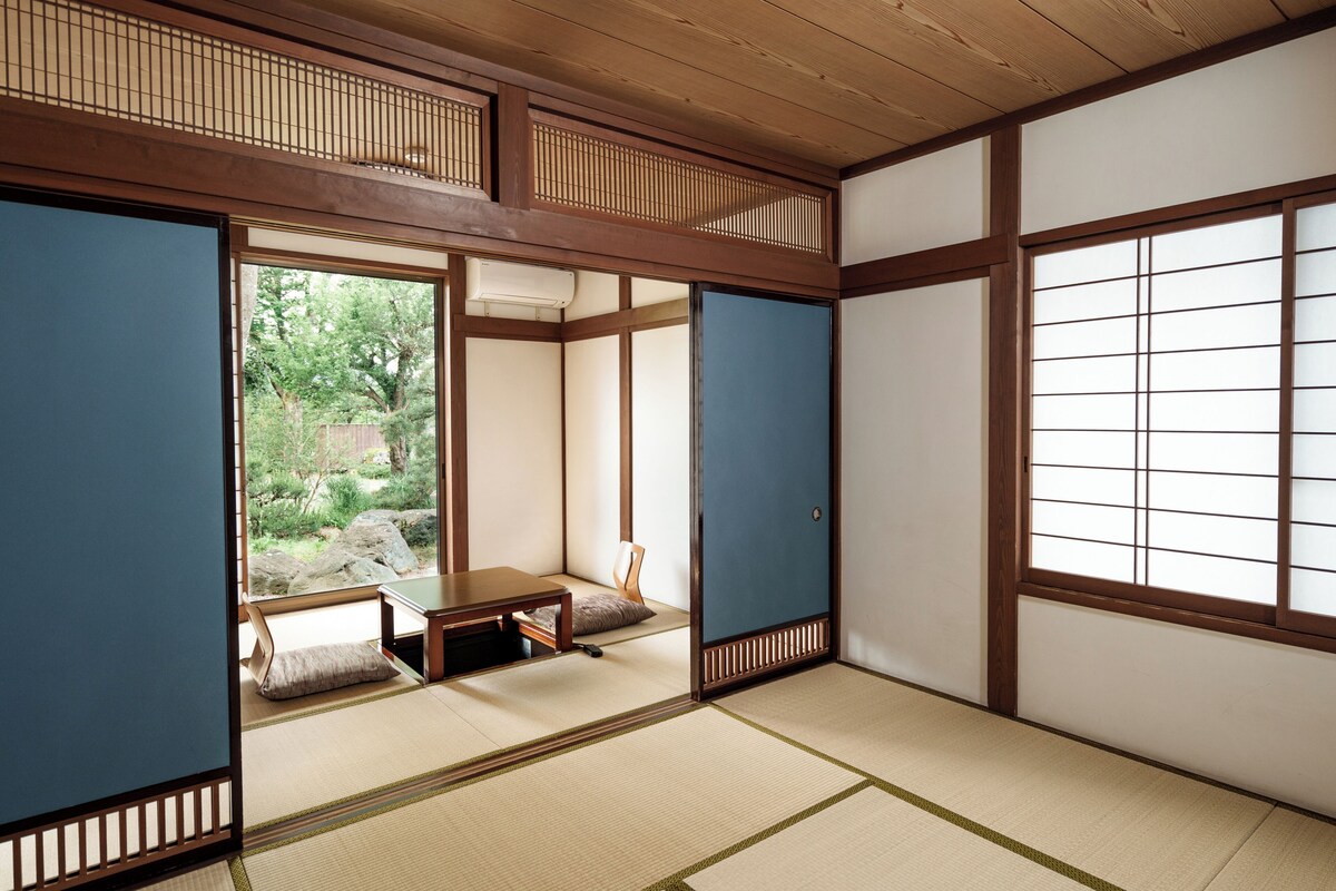 Um quarto japonês tradicional com tatames, portas deslizantes e vista para um jardim.