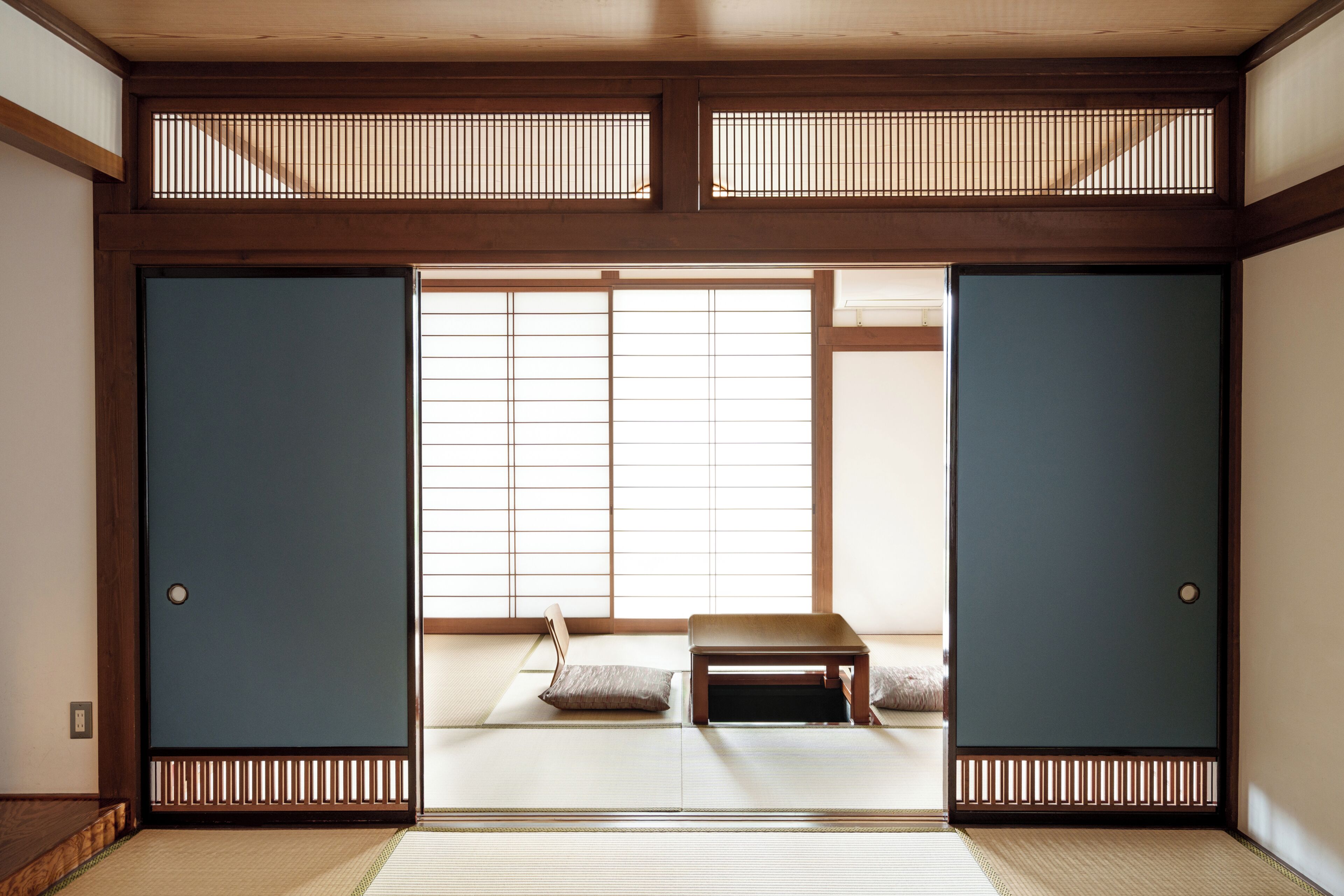 A traditional Japanese room with tatami flooring, sliding doors, and a low wooden table.