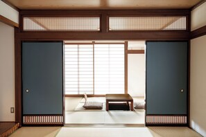 Una habitación japonesa tradicional con suelo de tatami, puertas correderas y una mesa de madera baja.