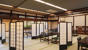 A traditional Japanese room with tatami flooring, shoji screens, and a low table with chairs.