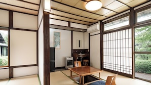 A traditional Japanese room with tatami flooring, a low wooden table, and a sliding door with a view of greenery.
