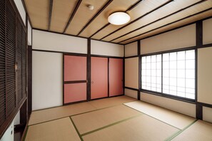Una habitación japonesa tradicional con suelo de tatami, puertas correderas y un ventanal grande.