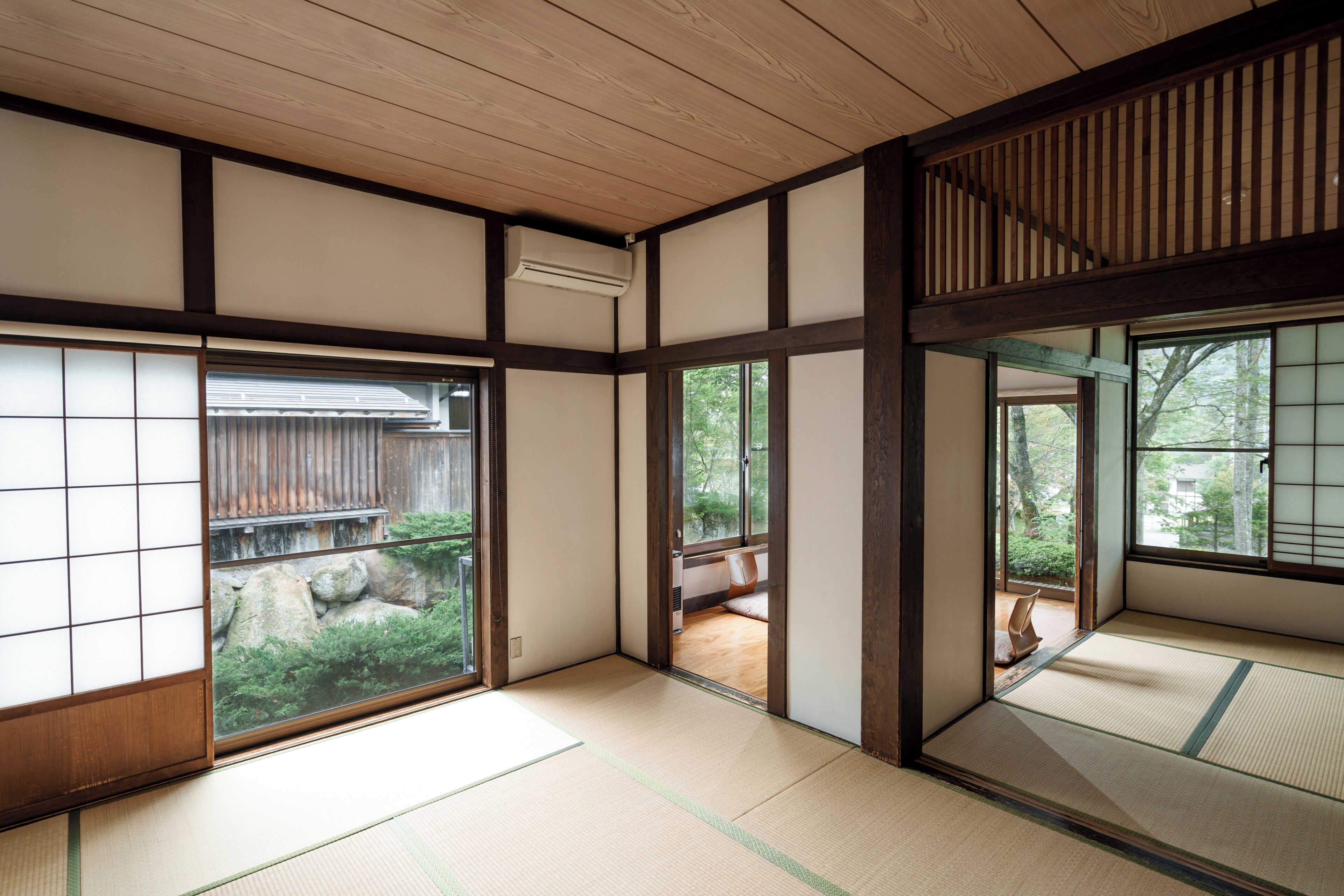 Une pièce de style japonais traditionnel, avec un sol recouvert de tatamis, des portes coulissantes et une vue sur un jardin.