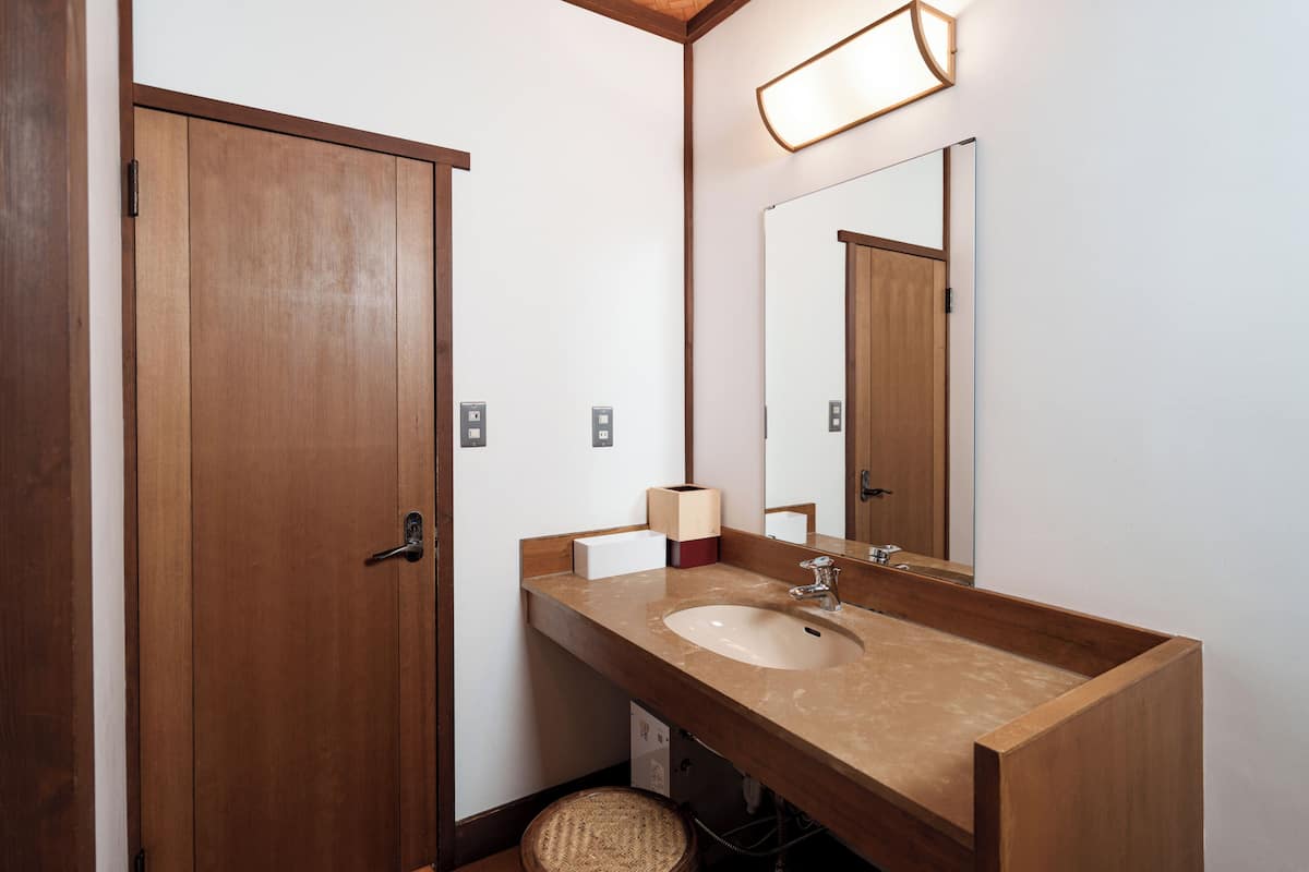 Ein Badezimmer aus Holz mit Waschbecken, Spiegel und Seifenspender.