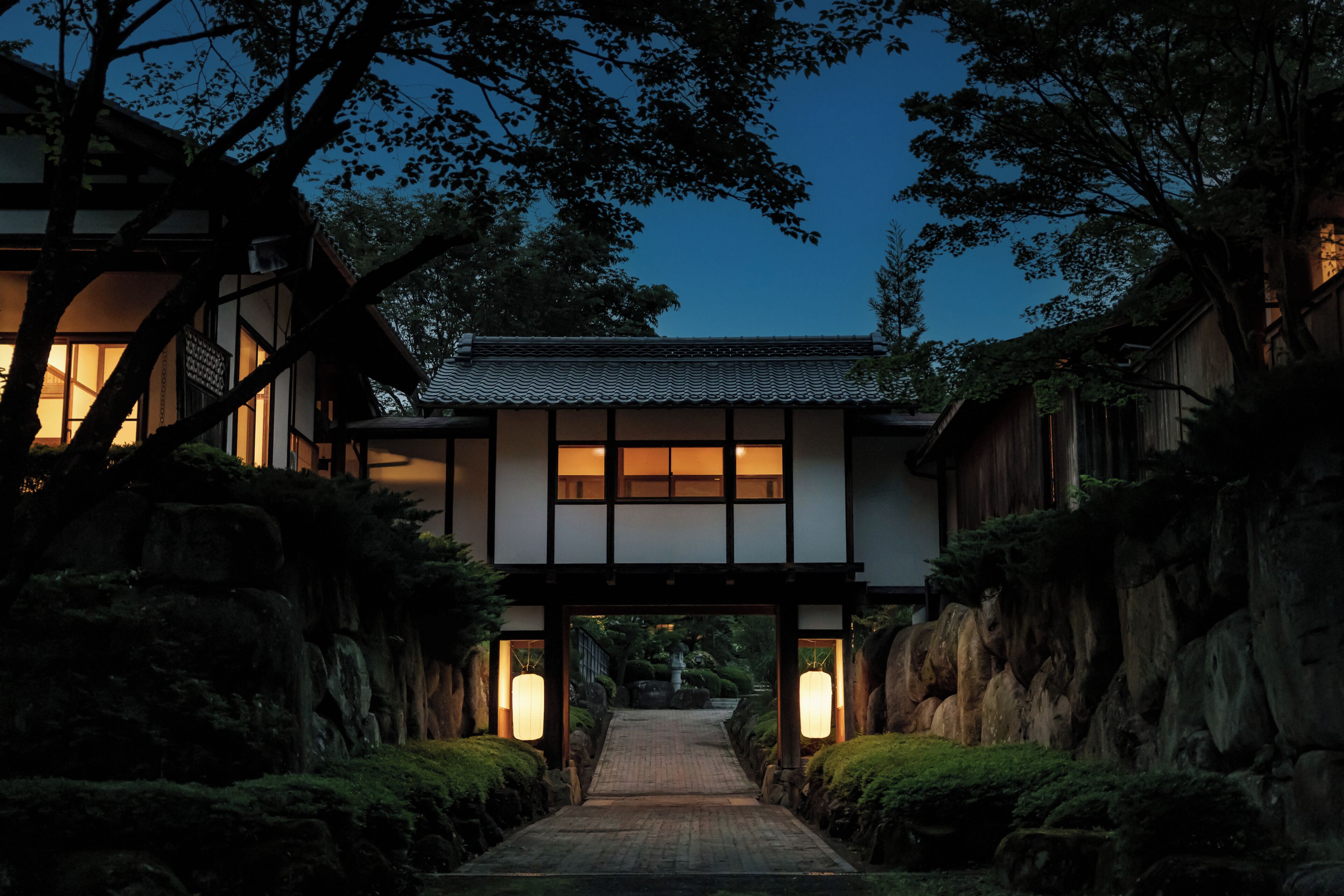 A traditional Japanese building with a wooden structure, a tiled roof, and a pathway leading to the entrance.