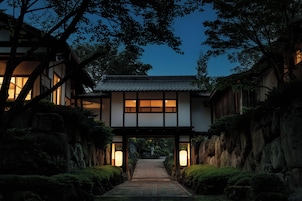 A traditional Japanese building with a wooden structure, a tiled roof, and a pathway leading to the entrance.