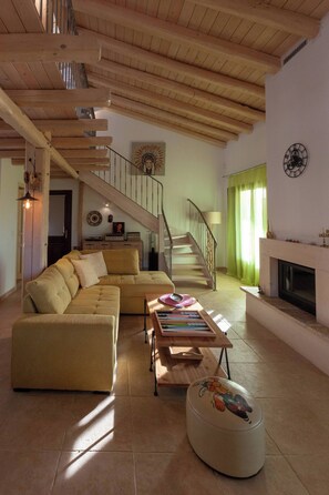 A spacious living room with a wooden staircase, a sofa, a coffee table, and a fireplace. - Perfect Escape Luxurious Villa Anastasia Tranquil Retreat in Arkadades Greece (Arkadades)