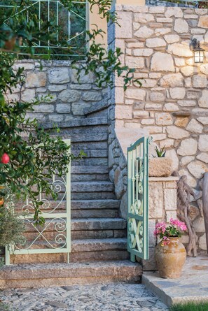 A stone staircase leading to a door, a potted plant, and a wall-mounted light fixture. - Perfect Escape Luxurious Villa Anastasia Tranquil Retreat in Arkadades Greece (Arkadades)