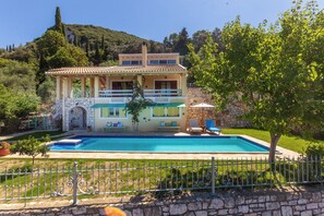A two-story house with a swimming pool, stone walls, and a view of a hill. - Perfect Escape Luxurious Villa Anastasia Tranquil Retreat in Arkadades Greece (Arkadades)