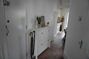 Un couloir avec une armoire blanche, une plante et un cadre photo.