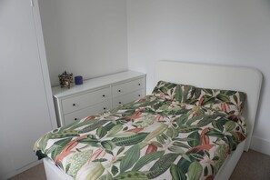 A bedroom with a bed, a white dresser, and a small shelf with a blue container. - Cosy 1BDR | Central Brighton | Near Station (Brighton and Hove)