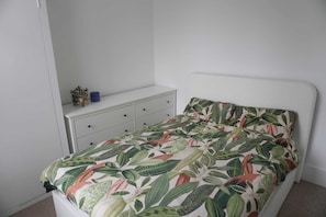 Ein Schlafzimmer mit einem Bett, einer weißen Kommode und einem kleinen dekorativen Gegenstand auf der Kommode.