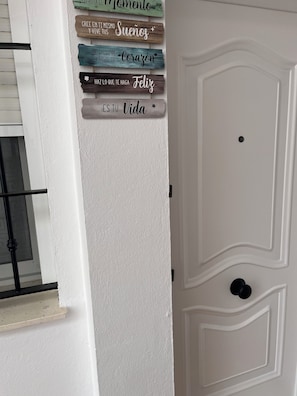 A white door with a decorative panel featuring wooden signs with inspirational messages.
