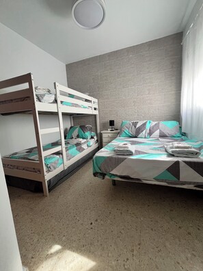 A room with bunk beds, a nightstand, and a window with curtains.