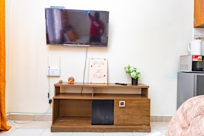 Ein modernes Wohnzimmer mit einem an der Wand montierten Flachbildfernseher, einer Holztv-Bank mit einer kleinen Ablage, einer Steckdose und einem gerahmten Motivationszitat.