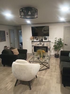 Ein modernes Wohnzimmer mit Flachbildfernseher, Kamin und Couchtisch.
