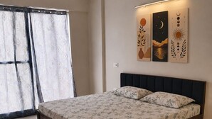 Ein Schlafzimmer mit Bett, Vorhängen, Deckenventilator und Wandbildern.