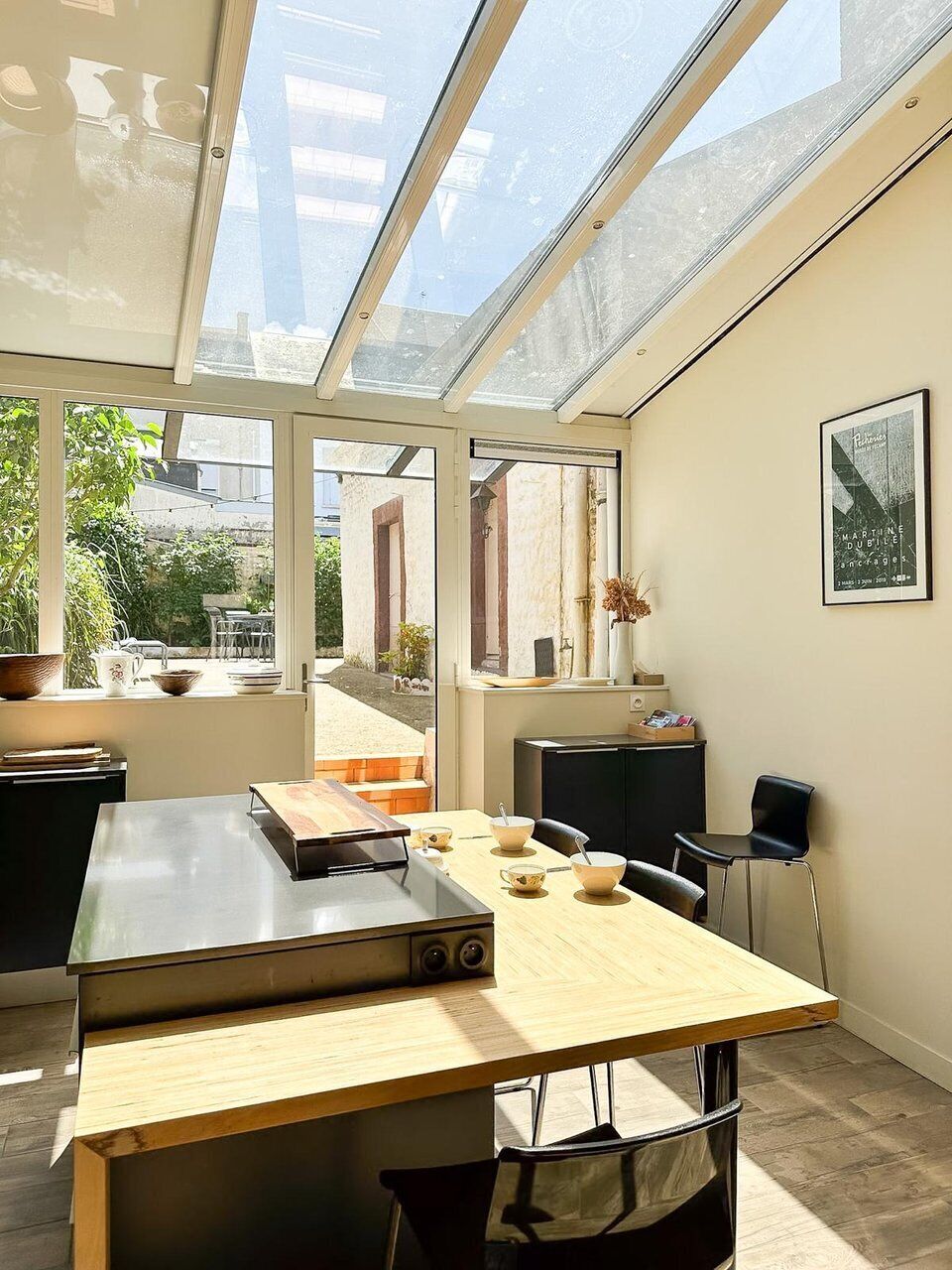 Eine moderne Küche mit einer großen Kochinsel, einem Esstisch und einer Glasdecke.