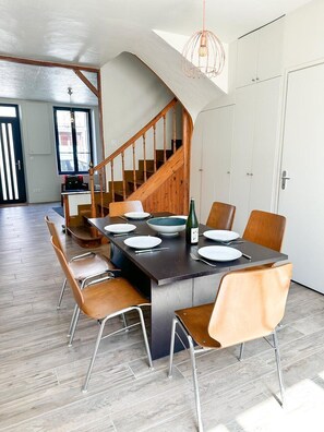 Un comedor con una mesa de madera oscura, platos blancos y una botella de vino.