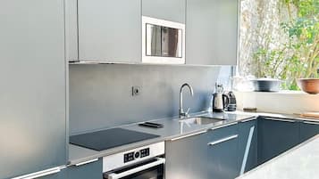 Een moderne keuken met grijze kastjes, een ingebouwde oven, een magnetron en een spoelbak.