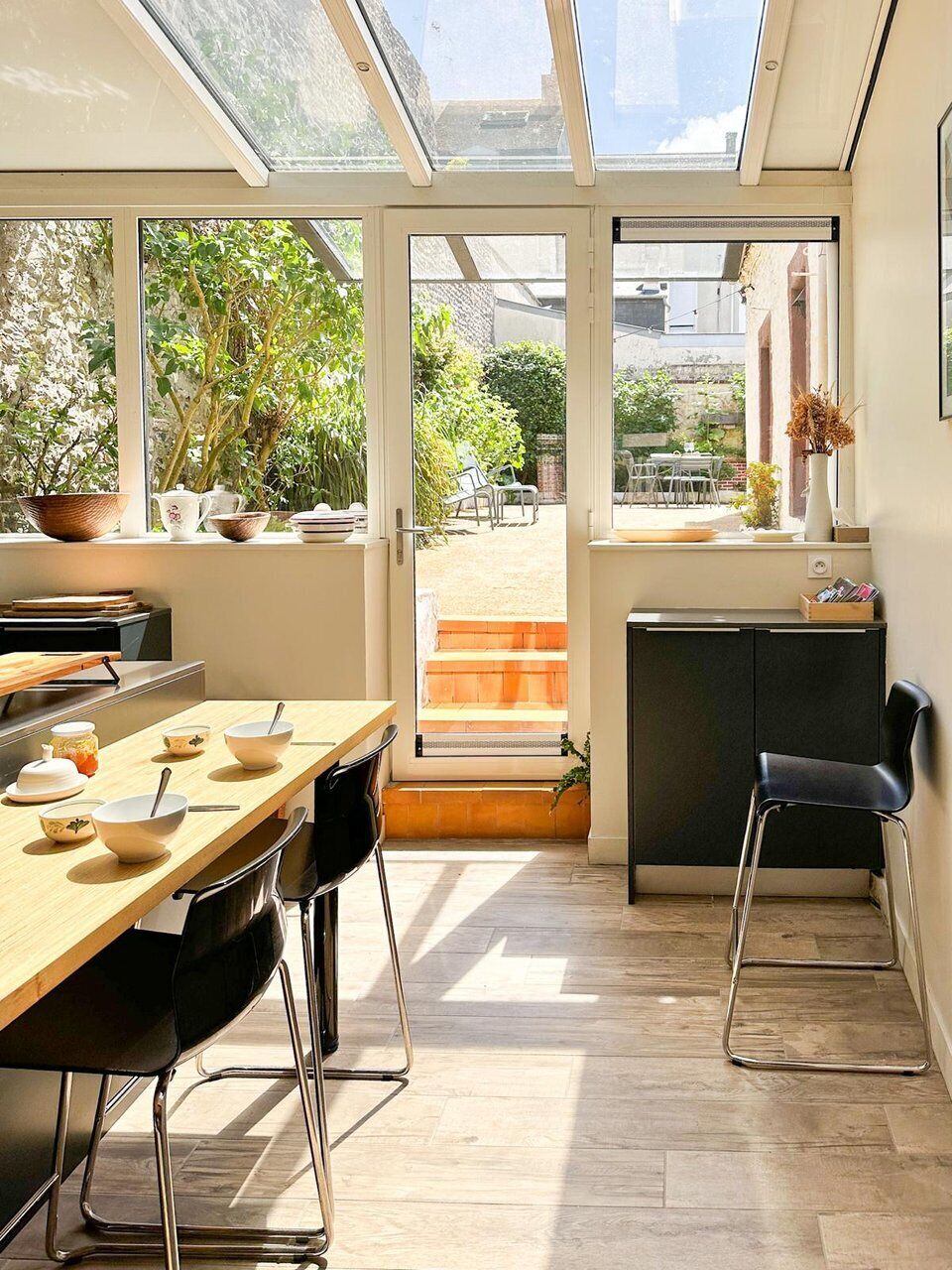 Een moderne keuken met een eethoek, grote ramen en uitzicht op de tuin.