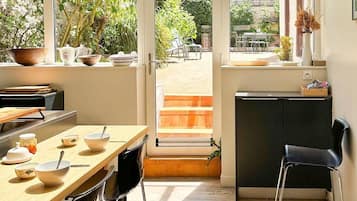 Een moderne keuken met een eethoek, grote ramen en uitzicht op de tuin.