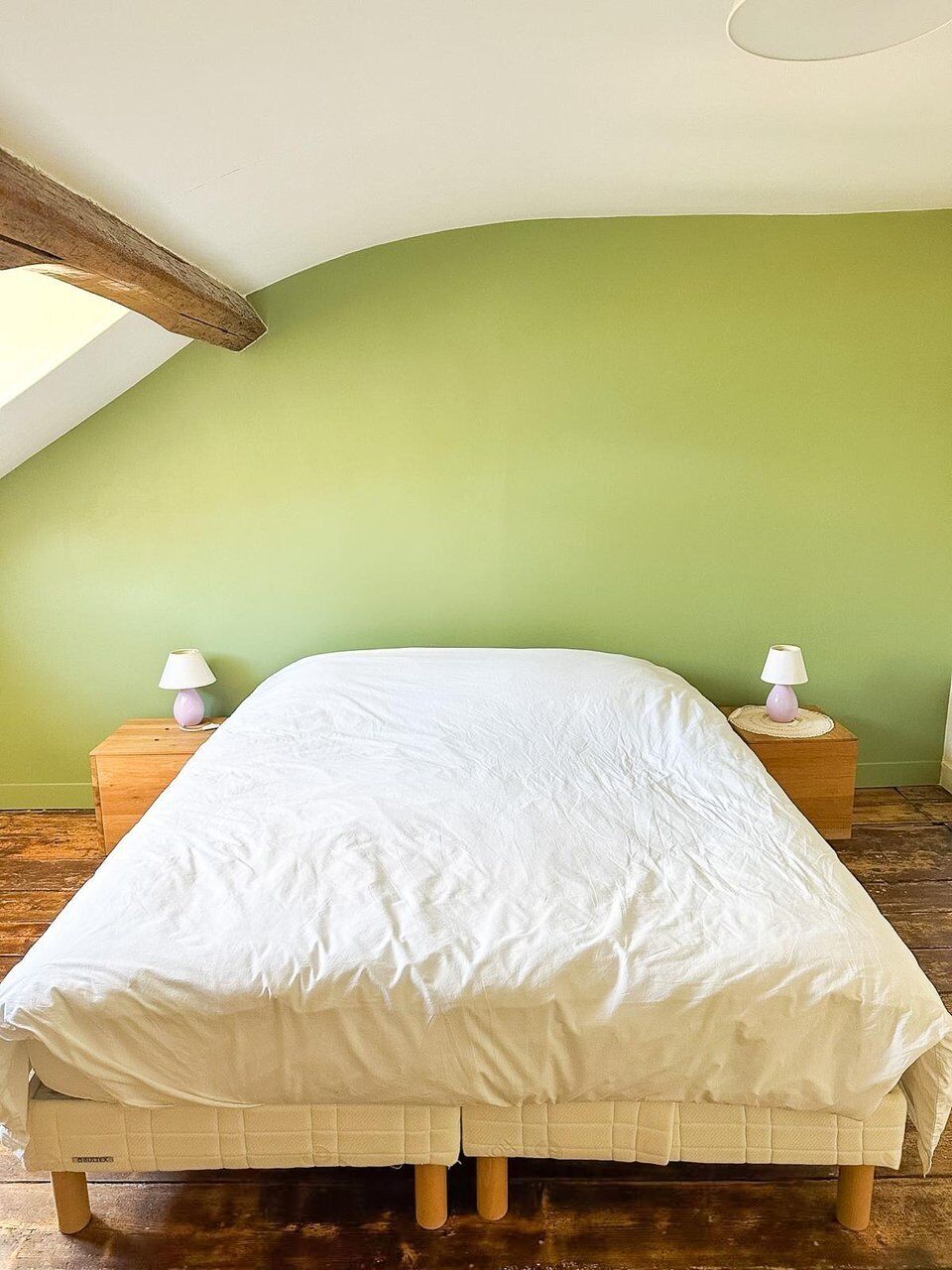 A single bed in a room with a sloped ceiling and green walls.