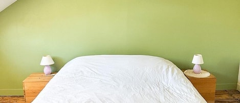 A single bed in a room with a sloped ceiling and green walls.