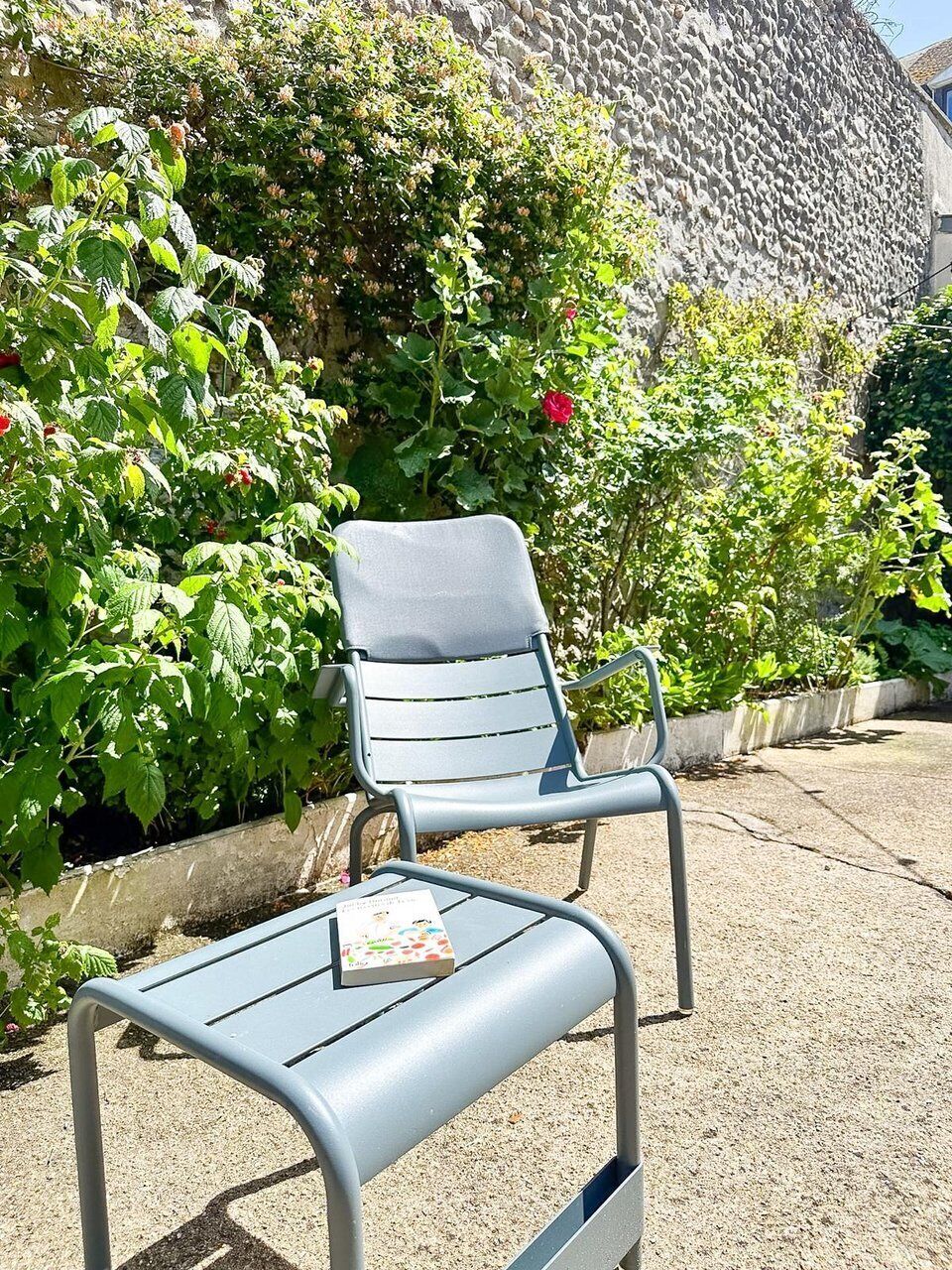 A metal chair with a book on it, placed on a concrete surface.
