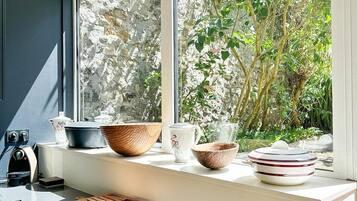Eine Küche mit einem großen Fenster, einem Schneidebrett und verschiedenen Schüsseln und Tellern auf der Arbeitsfläche.