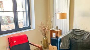 A room with a window, a blue sofa, a red chair, a lamp, and a radiator.