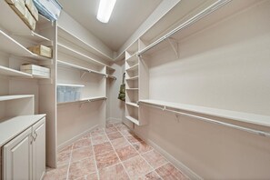 A walk-in closet with open shelving, a hanging rod, and a tiled floor.
