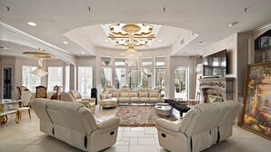 A spacious living room with a large sofa, two armchairs, a coffee table, and a chandelier.