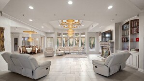 A spacious living room with a high ceiling, a fireplace, and a television.