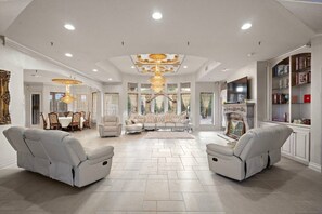 Un salon spacieux avec un plafond haut, une cheminée et un téléviseur.