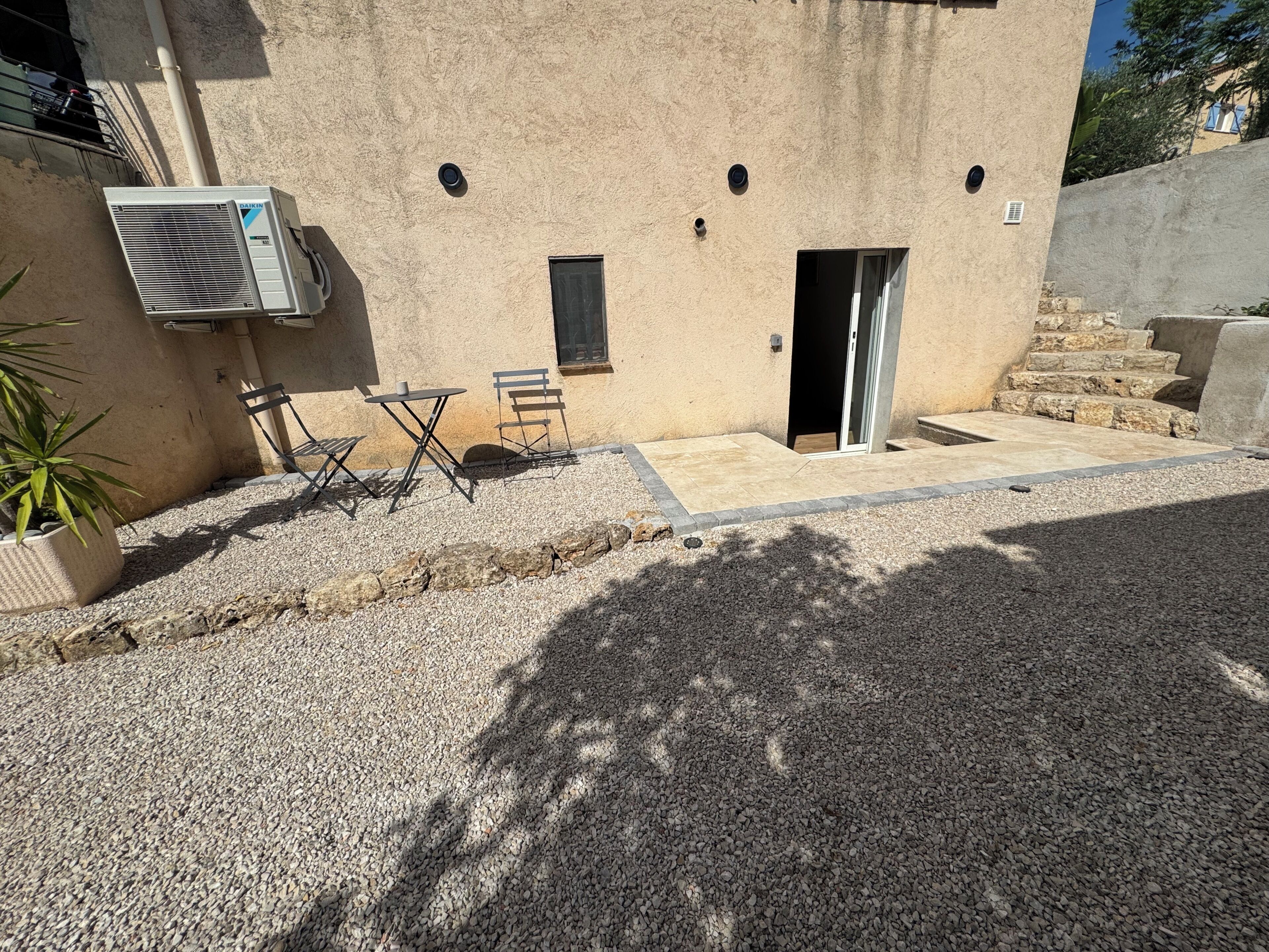 A building with a flat roof, a Daikin air conditioning unit, a small door, and a window.