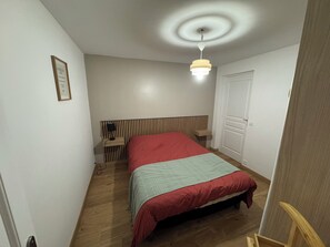 Ein Schlafzimmer mit Bett, Nachttisch, Lampe und Deckenleuchte.